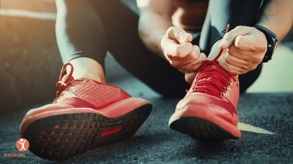 Sportler schnürt rote Laufschuhe vor dem Training
