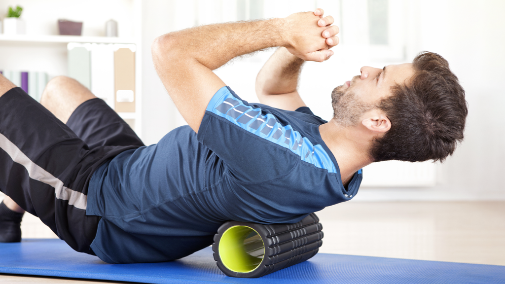 Mann beim Training mit einer Faszienrolle auf einer blauen Matte