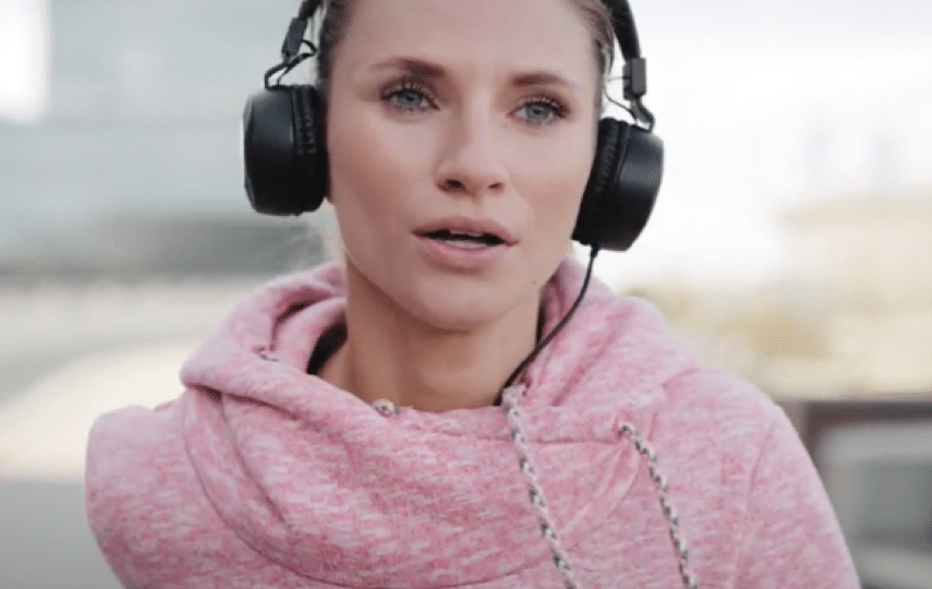 Frau in Sportkleidung mit Kopfhörern beim Walken im Freien