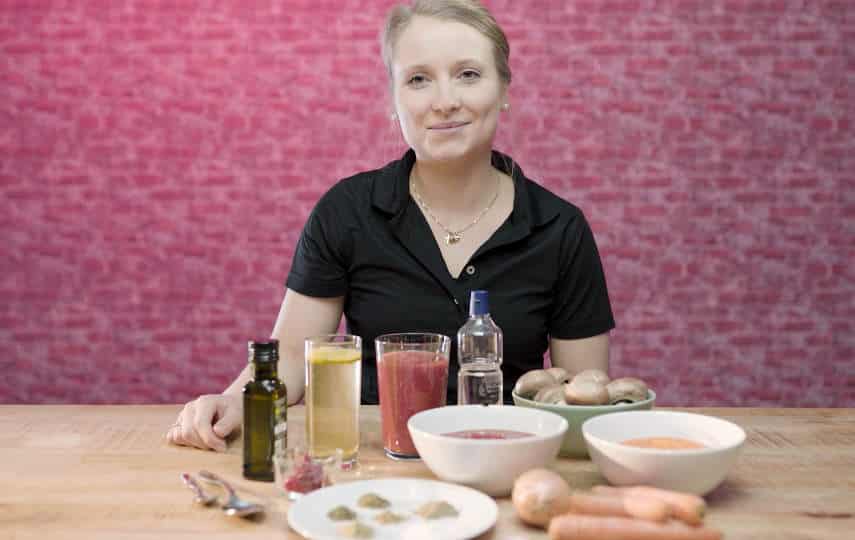 Frau am Tisch mit frischen Lebensmitteln und Getränken im Ernährungscoaching